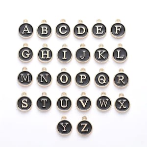 May include: A set of 26 gold-colored metal alphabet charms. Each charm is a black circle with a gold letter in the center. The letters are in alphabetical order from A to Z.