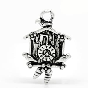 May include: Silver charm in the shape of a cuckoo clock with a bird on each side and a clock face with Roman numerals.