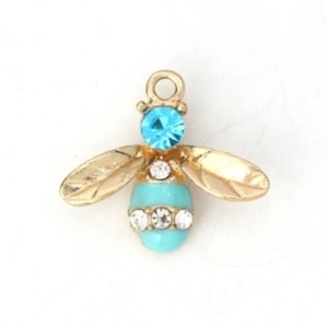 May include: Gold bee charm with turquoise and clear rhinestones. The bee has a gold loop for attaching to a necklace or bracelet.
