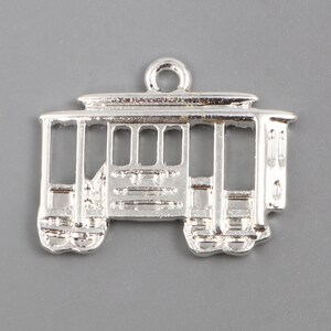 May include: Silver charm in the shape of a vintage streetcar. The charm has a detailed design with windows and a roof.