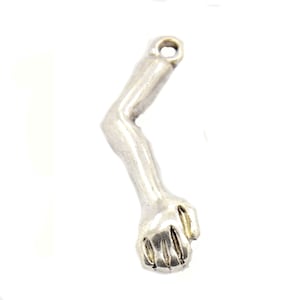 May include: Silver charm in the shape of a human arm with a closed fist.