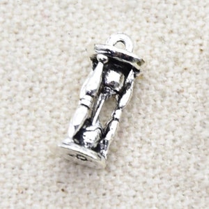 May include: Silver charm in the shape of an hourglass. The charm is detailed and has a loop at the top for attaching to a bracelet or necklace.