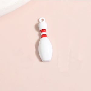 May include: White ceramic bowling pin charm with red stripes.
