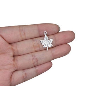 May include: Silver-toned maple leaf charm with a loop at the top for attaching to jewelry or crafts.