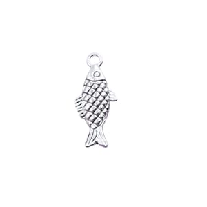 May include: A silver-colored fish charm with a textured scale pattern. The charm has a loop at the top for attaching to a necklace or bracelet. The fish has fins and a tail, and is set against a white background.