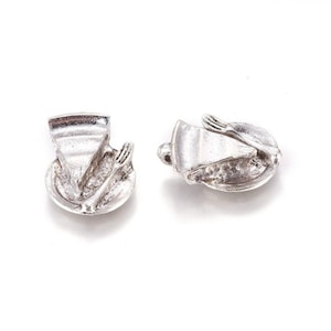 May include: Two silver charm pendants in the shape of a pie slice on a plate with a fork.