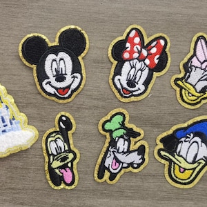 May include: Set of nine embroidered iron-on patches featuring Disney characters, including Mickey Mouse, Minnie Mouse, Donald Duck, Goofy, and Cinderella's castle.