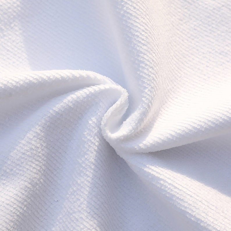 May include: Close-up of a white, textured fabric with a soft, plush feel. The fabric is folded and shows the texture and weave.