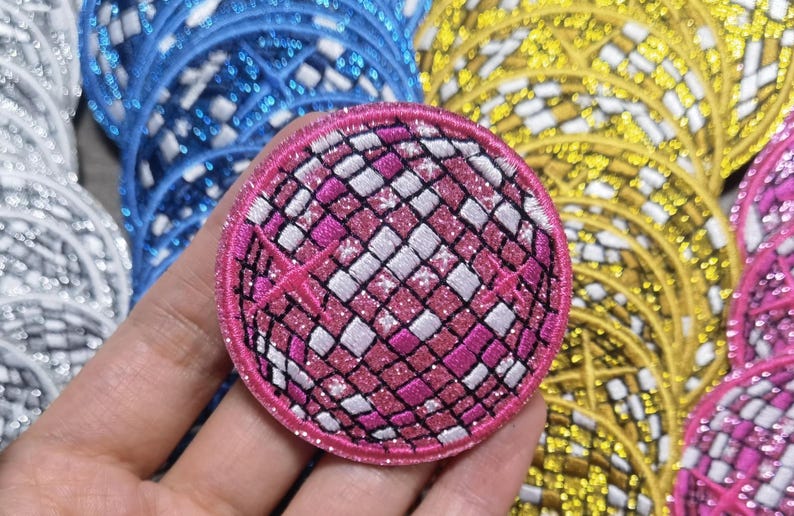 Op de afbeelding: Een ronde, roze en witte glitter discobal-strijkpatch. De patch heeft een glinsterende afwerking.