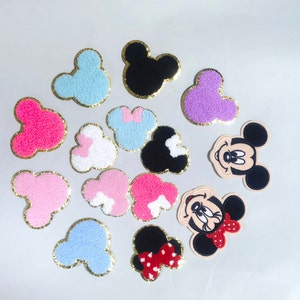 May include: Assortment of felt Mickey Mouse head appliques in various colors, including pink, blue, purple, and black. Some appliques have gold glitter trim.