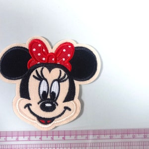 May include: Embroidered iron-on patch featuring a cartoon image of Minnie Mouse with a red bow with white polka dots. The patch is approximately 5 cm in diameter.