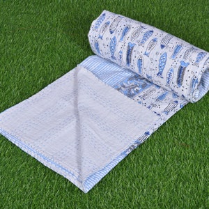 May include: A white and blue kantha quilt with a fish pattern. The quilt is folded in half and rolled up, with the fish pattern visible on the outside.