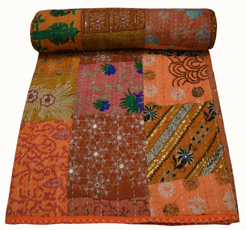 May include: A patchwork quilt with a variety of colors and patterns, including orange, brown, pink, and green. The quilt is made of cotton fabric and is decorated with embroidery and sequins.