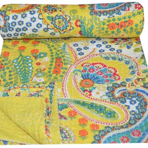 Puede incluir: Una colcha kantha amarilla con un patr&oacute;n de paisley en tonos de azul, verde, rojo y naranja. La colcha est&aacute; cosida a mano y tiene un dise&ntilde;o tradicional indio.
