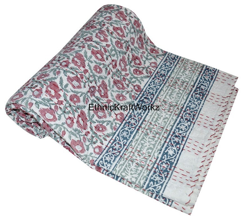 May include: A white cotton quilt with a floral print in shades of pink and green. The quilt has a blue and green border with a floral pattern. The quilt is rolled up and the text "EthnicKraftWorkz" is visible.