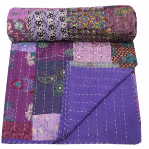 May include: Purple kantha quilt with a patchwork design featuring floral and paisley patterns. The quilt is made of recycled saris and is hand-stitched.