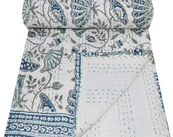 May include: A white cotton kantha quilt with a blue and green floral pattern. The quilt is folded in half and has a decorative border.