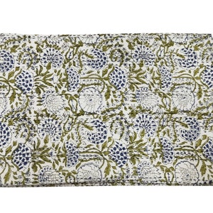 May include: A white cotton quilt with a green and blue floral pattern. The quilt is folded in half and has a stitched edge.