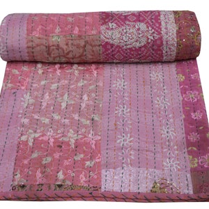 Könnte beinhalten: Rosa Kantha-Steppdecke mit floralen Stickereien und Paisley-Mustern. Die Decke ist aus recycelten Saris gefertigt und handgenäht.