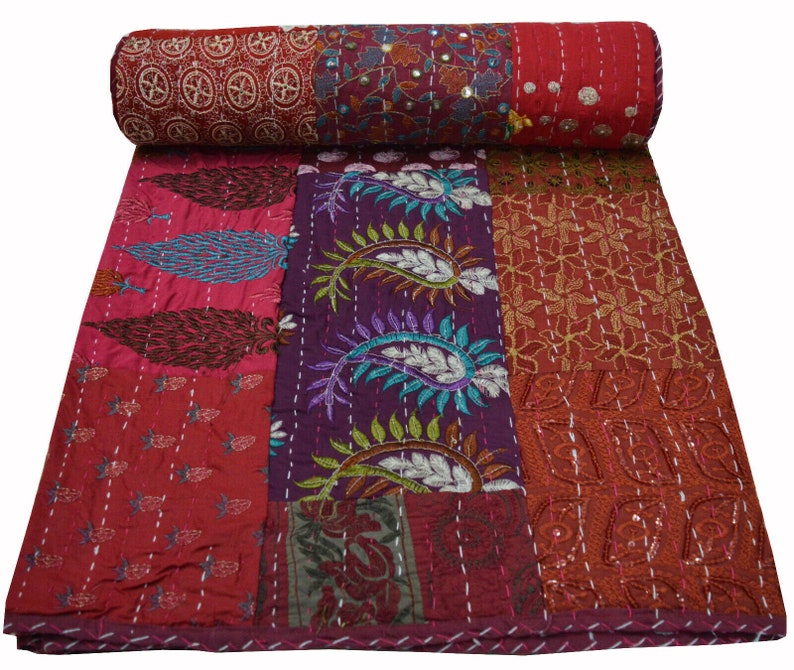 May include: A patchwork quilt with a variety of colors and patterns, including red, purple, and brown. The quilt is made of different fabrics and has a hand-stitched look. It is a traditional Indian kantha quilt.