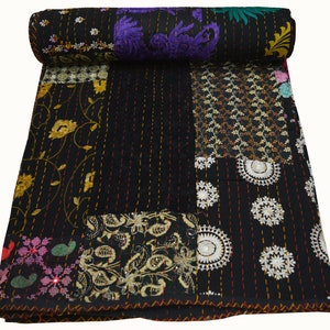 May include: Black kantha quilt with a patchwork design featuring various floral and geometric patterns in shades of gold, white, and purple. The quilt is made of cotton and is hand-stitched.