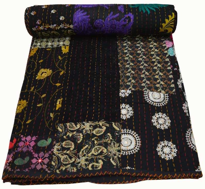 May include: Black kantha quilt with a patchwork design featuring various floral and geometric patterns in shades of gold, white, and purple. The quilt is made of cotton and is hand-stitched.