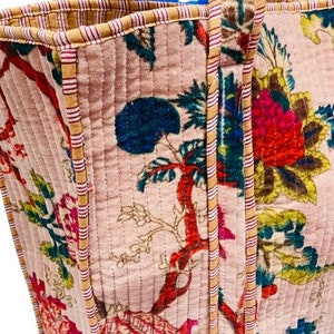 May include: A pink quilted tote bag with a floral print and striped trim. The bag has two handles and a zipper closure.