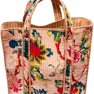 May include: A pink quilted tote bag with floral print and yellow and red striped trim. The bag has two handles.