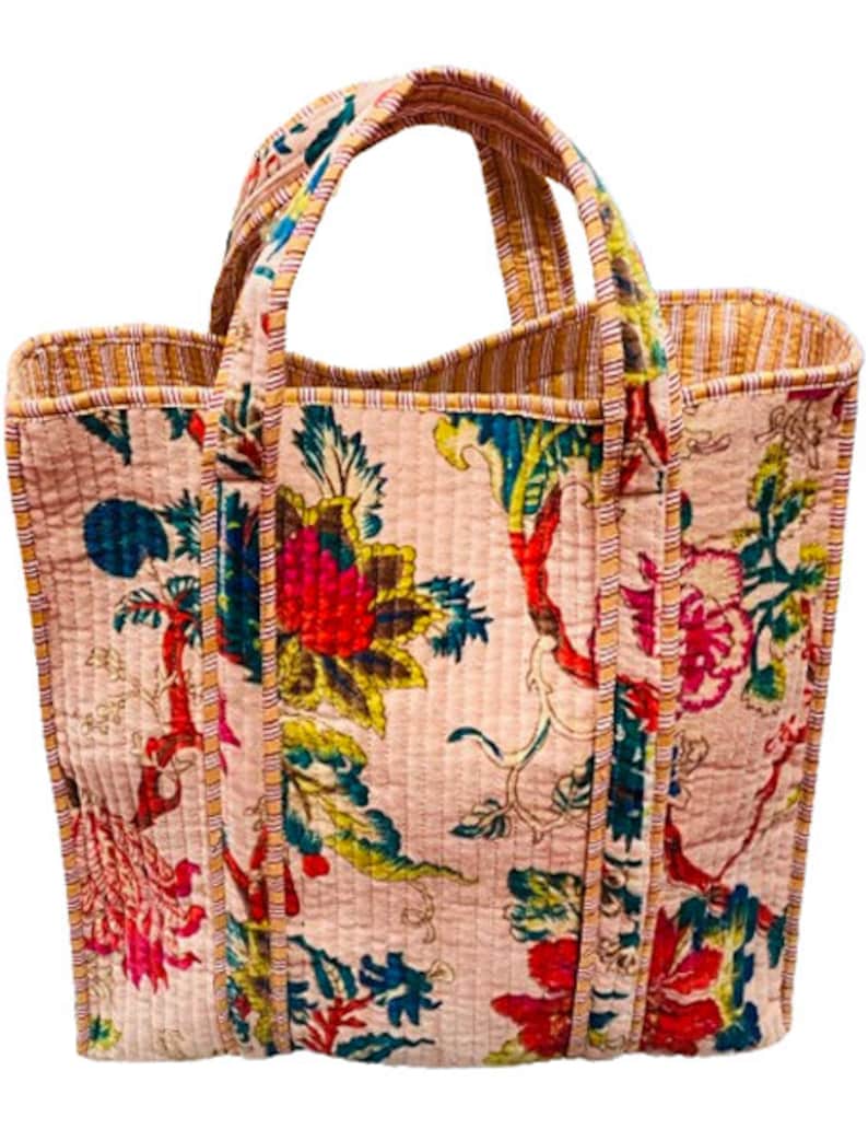 May include: A pink quilted tote bag with floral print and yellow and red striped trim. The bag has two handles.