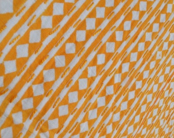 May include: White fabric with a yellow diamond pattern. The fabric has a textured surface.