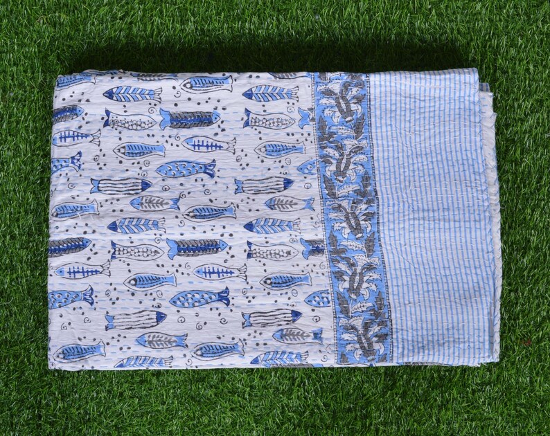 May include: A white and blue cotton quilt with a pattern of blue fish and floral designs. The quilt has a light blue border with white stripes.