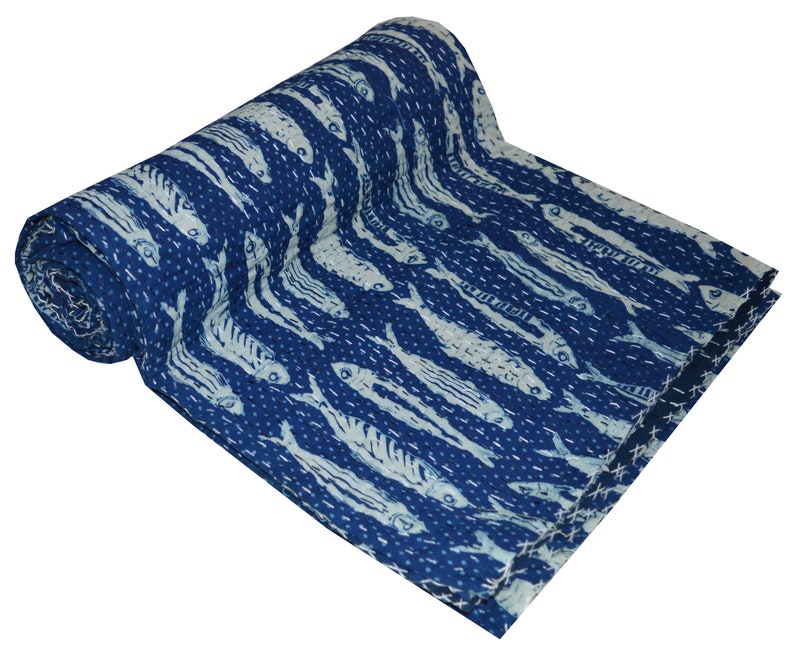 May include: A blue kantha quilt with a white fish pattern. The quilt is folded and rolled up, showing the intricate stitching and the design.