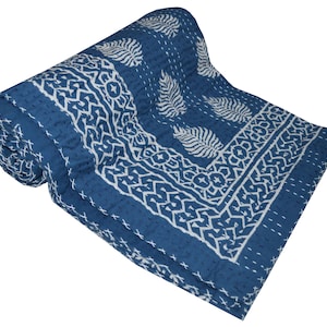 May include: A blue and white kantha quilt with a traditional Indian block print design. The quilt is folded and rolled up, revealing the intricate details of the pattern.