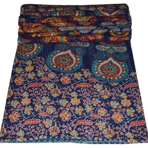 May include: A blue kantha quilt with a paisley and floral pattern. The quilt is folded and shows the stitching detail.