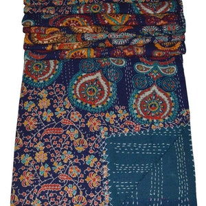 May include: A blue and teal kantha quilt with a paisley and floral pattern. The quilt is folded in half and has a decorative stitch pattern.