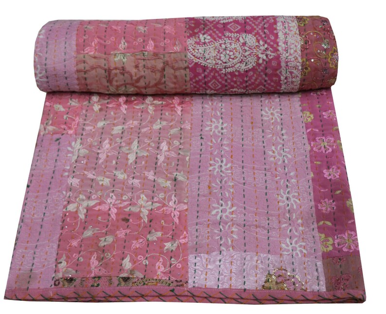 May include: Pink kantha quilt with a patchwork design featuring floral and paisley patterns. The quilt is made of cotton and has a hand-stitched kantha embroidery.