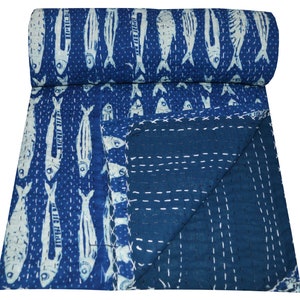 May include: A blue kantha quilt with a white fish pattern. The quilt is folded in half and the fabric is soft and textured.