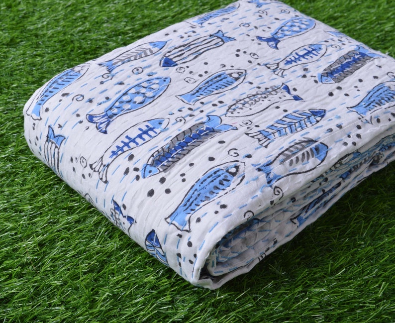 May include: White cotton fabric with a blue fish print. The fabric is folded and has a textured surface.