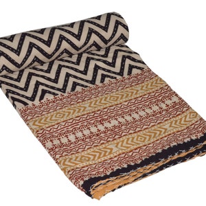 May include: A beige and black kantha quilt with a chevron pattern on one side and a geometric pattern on the other side. The quilt is folded and rolled up.