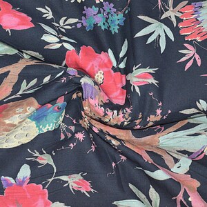 May include: A dark blue fabric with a floral print featuring pink and red flowers, green leaves, and brown birds. The fabric has a soft, flowing texture.