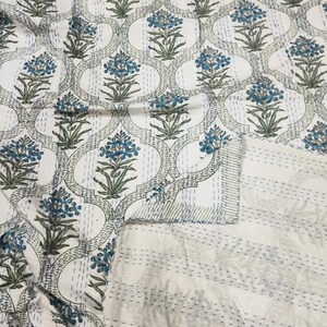May include: White cotton quilt with a blue and green floral pattern. The quilt is hand-stitched and has a traditional Indian design.