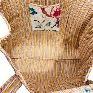 May include: A yellow and white striped tote bag with a floral print pocket and a floral print strap. The bag is made of quilted fabric.