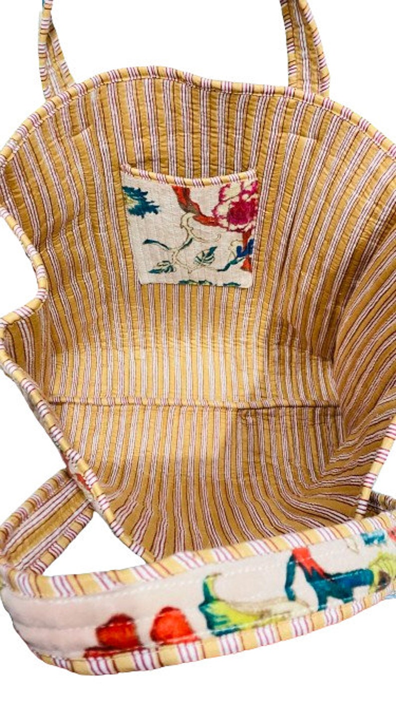 May include: A yellow and white striped tote bag with a floral print pocket and a floral print strap. The bag is made of quilted fabric.