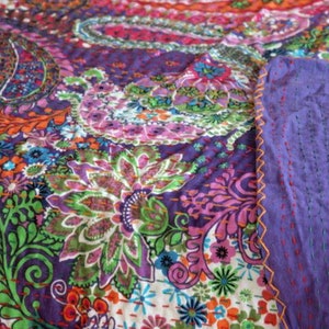 Puede incluir: Una colcha kantha colorida con un patr&oacute;n de paisley en tonos de morado, rosa, verde, naranja y azul. La colcha est&aacute; cosida a mano con una puntada corrida y tiene un respaldo morado.