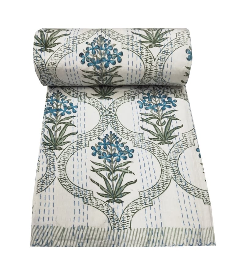 May include: White kantha quilt with a blue and green floral pattern. The quilt is rolled up and has a fringed edge.