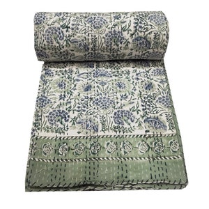 May include: A white kantha quilt with a green and blue floral pattern. The quilt is hand-stitched and has a green border.