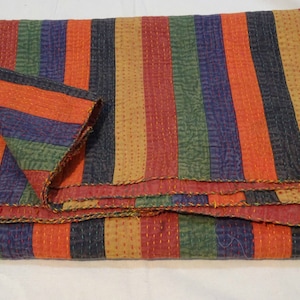 May include: A multi-colored striped kantha quilt with a hand-stitched design. The quilt is folded in thirds and features shades of orange, red, green, blue, and brown.