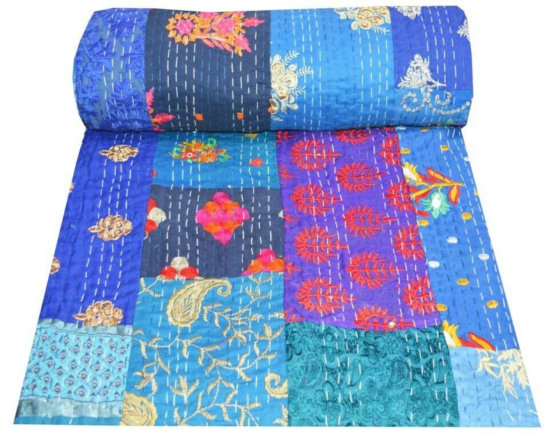 May include: A patchwork quilt with a blue background and colorful floral patterns. The quilt is made of various fabrics and is hand-stitched.