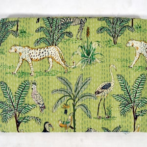May include: Green fabric with a repeating pattern of leopards, flamingos, palm trees, and other tropical plants. The fabric has a quilted texture.