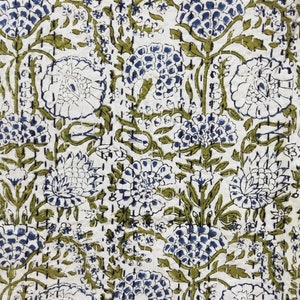 May include: A white fabric with a repeating pattern of blue and green flowers. The flowers are stylized and have a vintage look.
